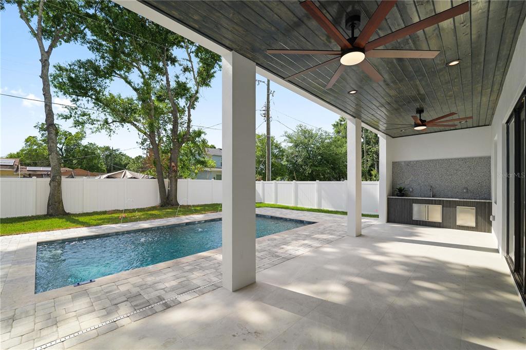A covered patio features a swimming pool, outdoor dining area, and dark wood-paneled ceiling — 2308 1/2 N ELCOE DRIVE, TAMPA, FL