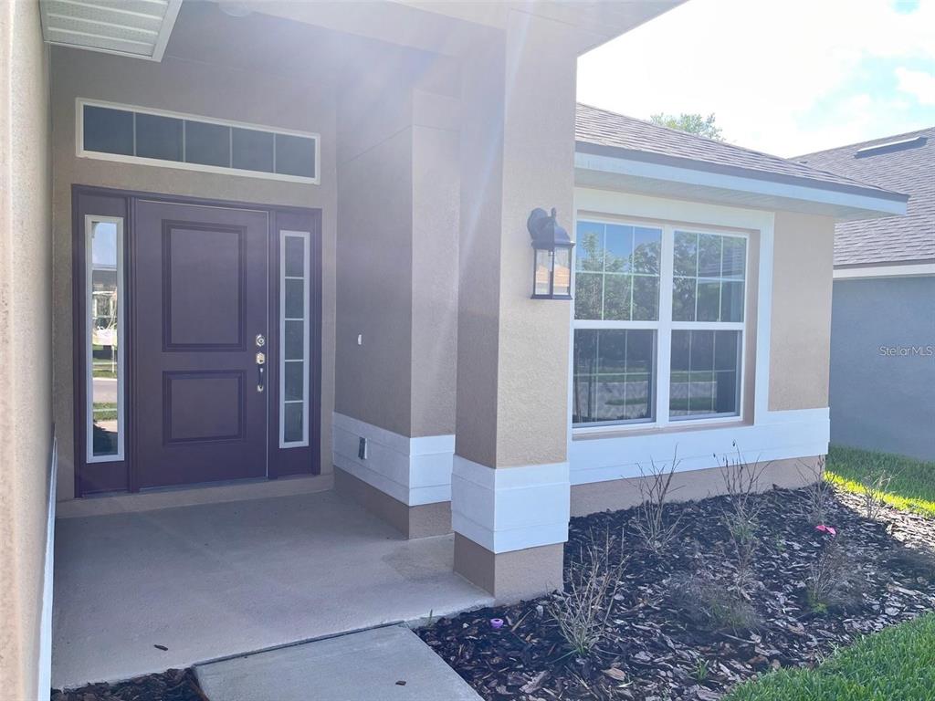 The exterior of a house features a purple front door, a covered porch, and windows — 13022 KENT BRADELY STREET, DADE CITY, FL
