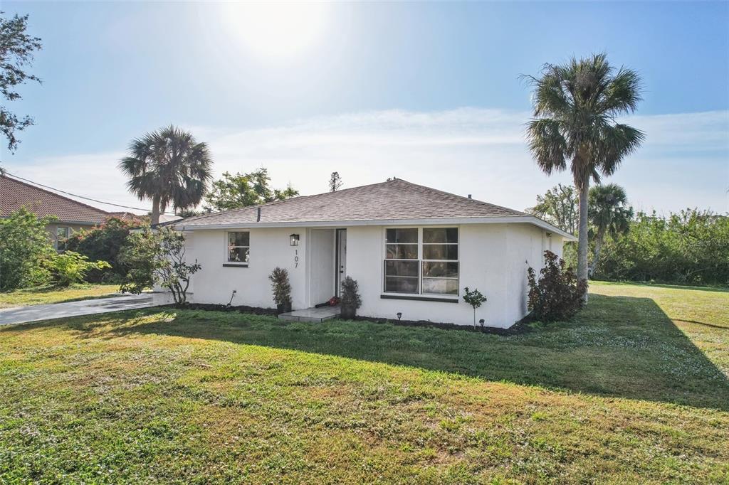 A single-story white house with a hip roof sits on a grassy lot with palms — 107 TEMPLE ROAD, VENICE, FL