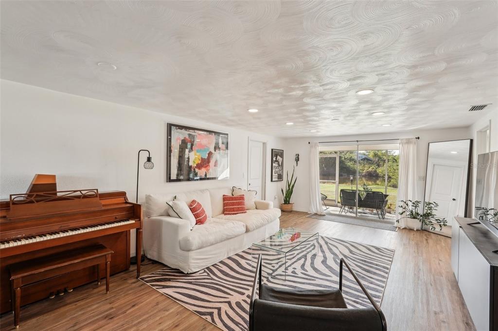 A living room features a piano, white sofa, zebra-print rug, and sliding doors to a patio — 107 TEMPLE ROAD, VENICE, FL