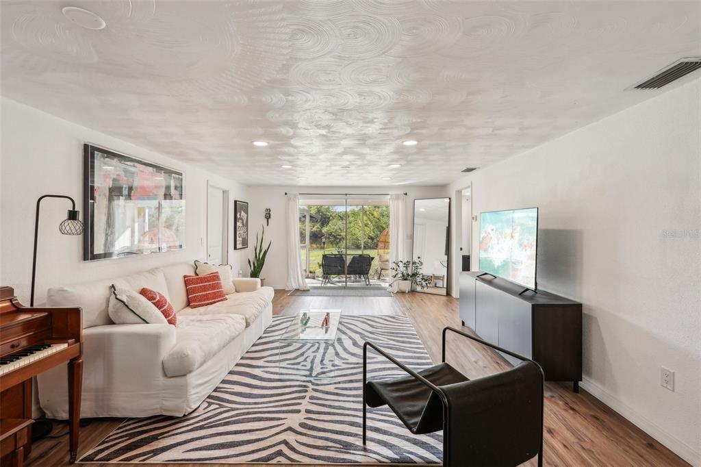 A living room features a white sofa, zebra-print rug, piano, and sliding glass doors to outdoors — 107 TEMPLE ROAD, VENICE, FL