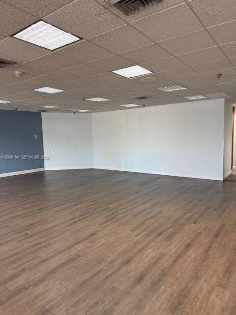 An empty office space features a drop ceiling, recessed lighting, and wood-look flooring — 9080 Kimberly Blvd # 4, Boca Raton FL 33434, BOCA RATON, FL