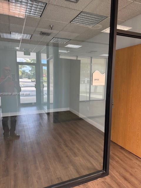 An empty office space features wood-look flooring, a drop ceiling, and floor-to-ceiling glass windows — 9080 Kimberly Blvd # 4, Boca Raton FL 33434, BOCA RATON, FL