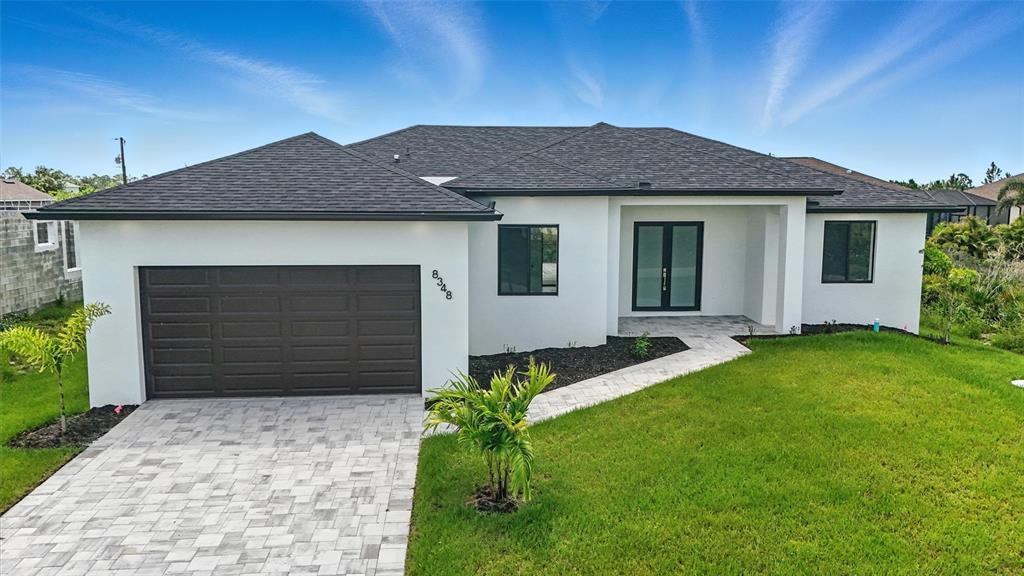 A single-story house with white stucco walls, a dark roof, and a paved driveway — 8348 WALDEN STREET, PORT CHARLOTTE, FL