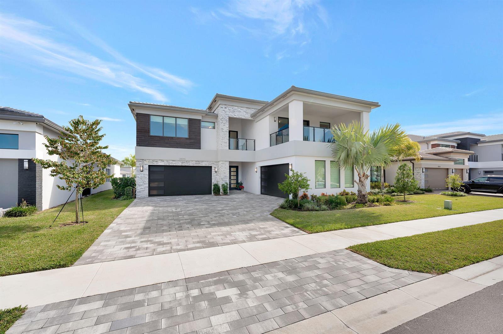 A two-story modern house features a stone facade, two garage doors, and a balcony — 20046 Pacific Dunes Drive, Boca Raton FL 33434, BOCA RATON, FL