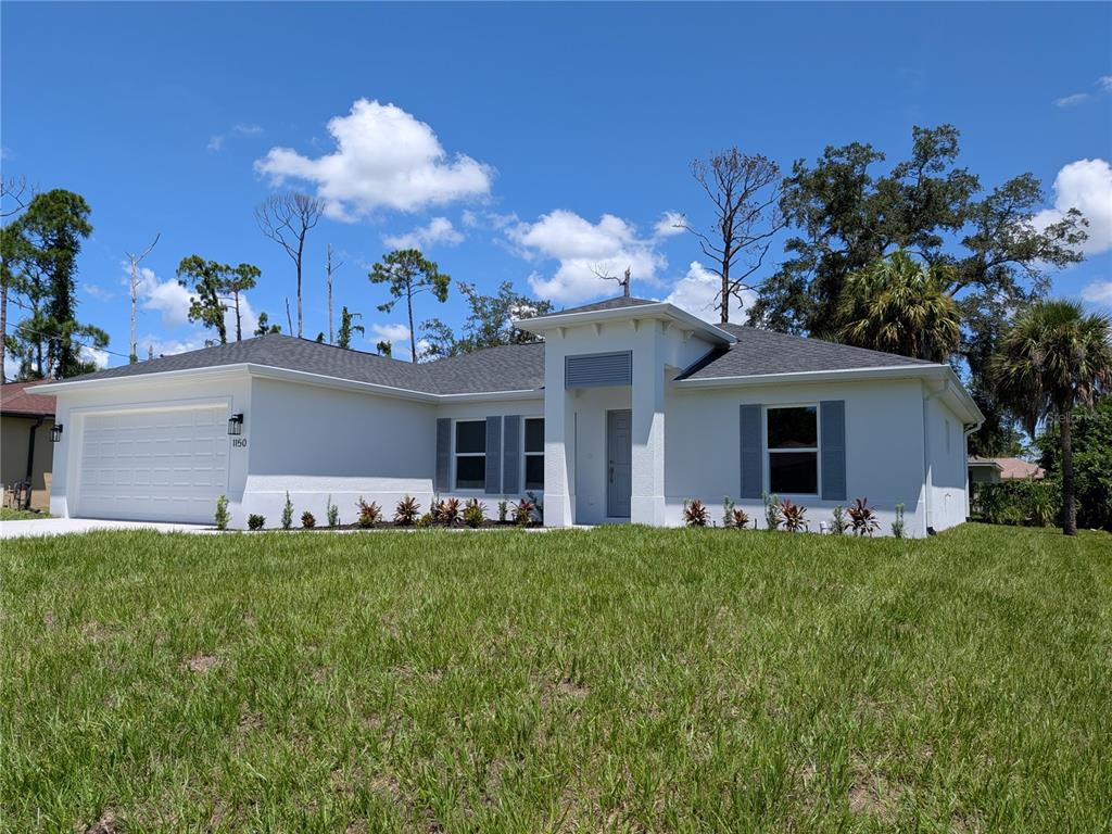 A single-story white house with a two-car garage and gray shutters under a blue sky — 1150 TALHEM AVENUE, NORTH PORT, FL