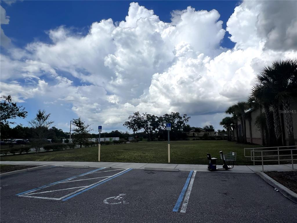 A paved parking lot with handicap spaces sits in front of a grassy field and sky — 12249 CORTEZ BOULEVARD, BROOKSVILLE, FL