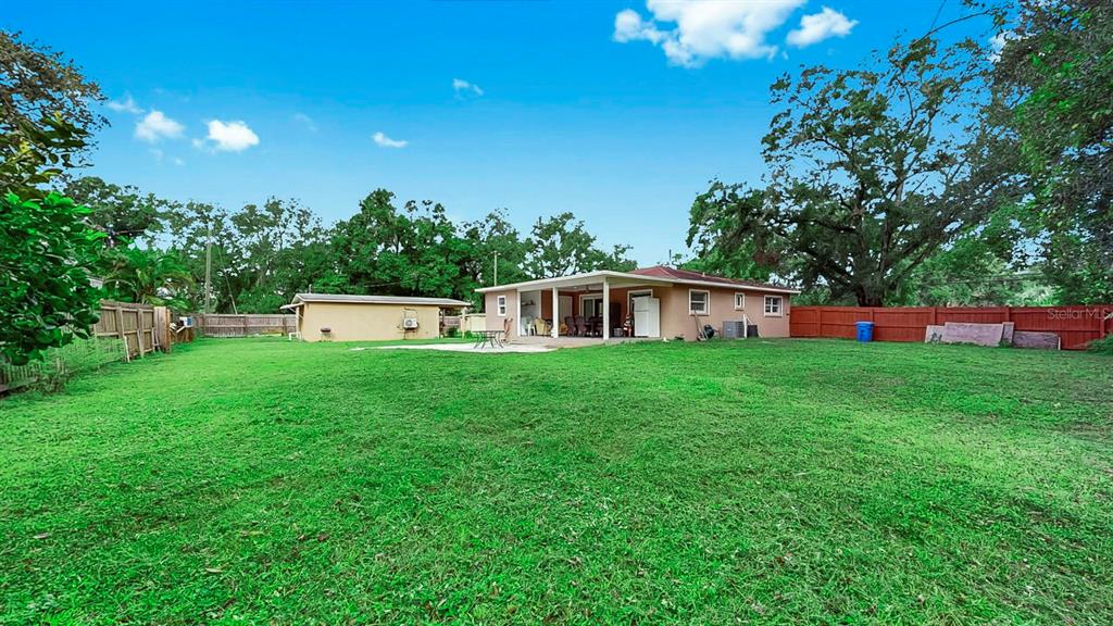 A backyard view of a single-story house with a covered patio and detached garage — 6003 16TH AVENUE S, TAMPA, FL
