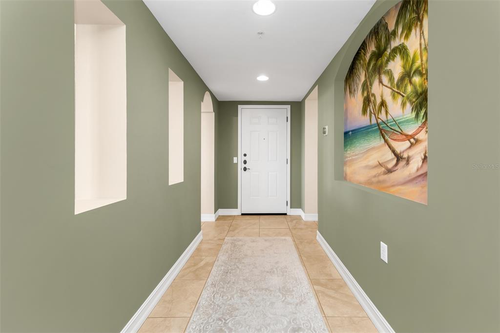 A hallway with sage green walls, tile flooring, recessed wall niches, and a white door — 3340 WOOD THRUSH DRIVE UNIT 241, PUNTA GORDA, FL