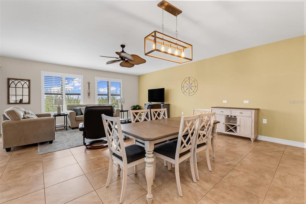 A dining area with a wooden table and chairs sits in front of a living room — 3340 WOOD THRUSH DRIVE UNIT 241, PUNTA GORDA, FL