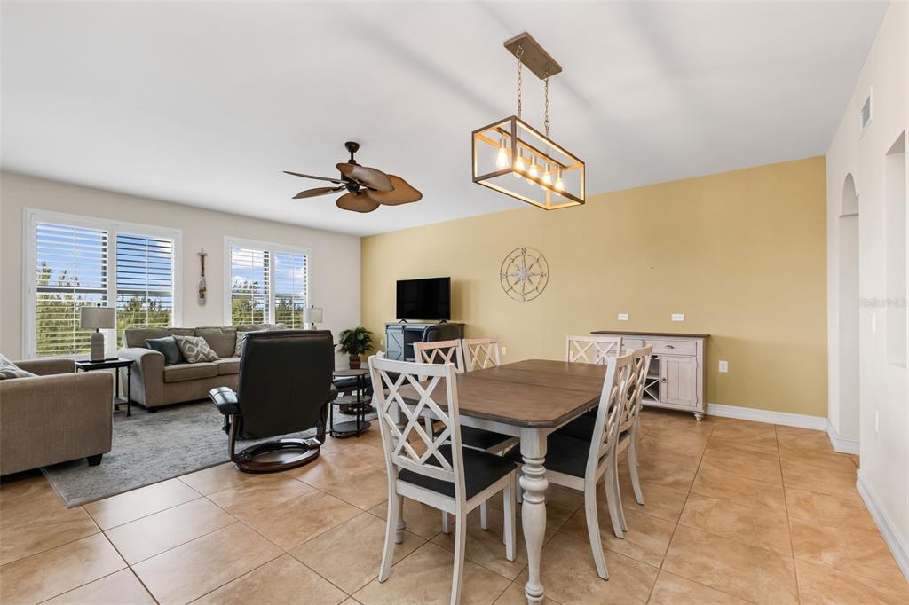 An open-concept living and dining area features tile flooring, a ceiling fan, and pendant lighting — 3340 WOOD THRUSH DRIVE UNIT 241, PUNTA GORDA, FL