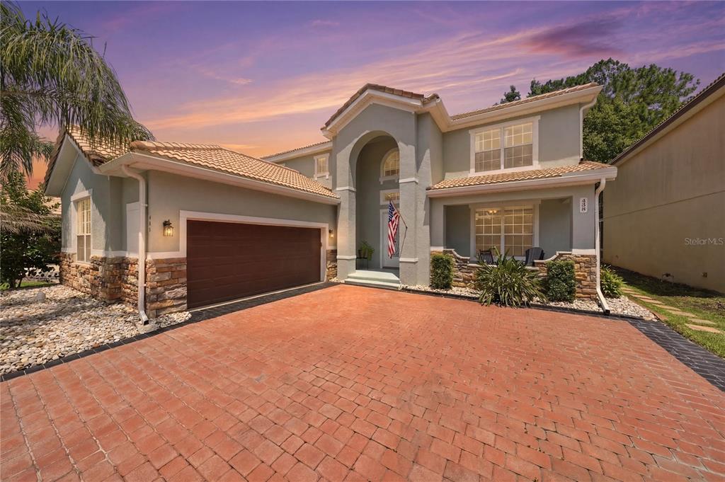 A two-story house with a brick driveway, a two-car garage, and a stone-accented exterior — 489 LUNA BELLA LANE, NEW SMYRNA BEACH, FL