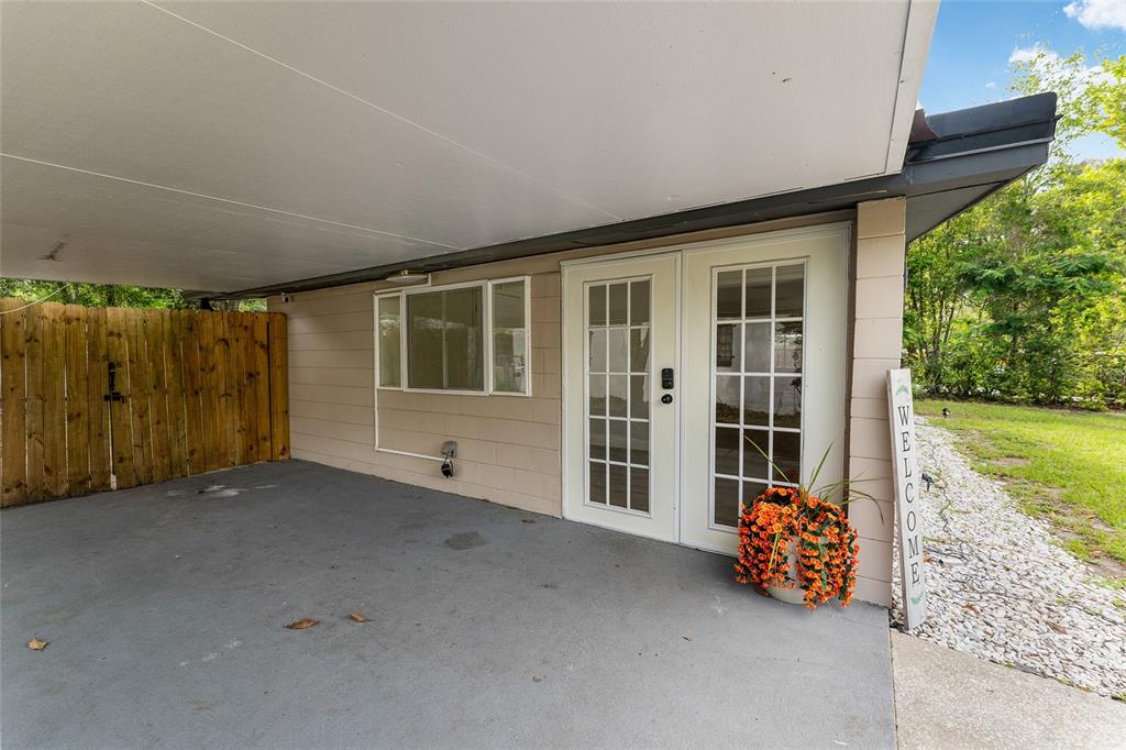 A covered concrete patio features a double glass door entrance and a wooden fence — 1753 NE 20TH PLACE, GAINESVILLE, FL