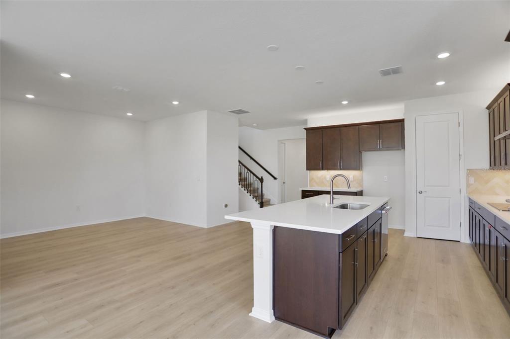 A modern kitchen features dark wood cabinets, a white quartz island, and light wood flooring — 13524 TURNLEAF BOULEVARD, PUNTA GORDA, FL