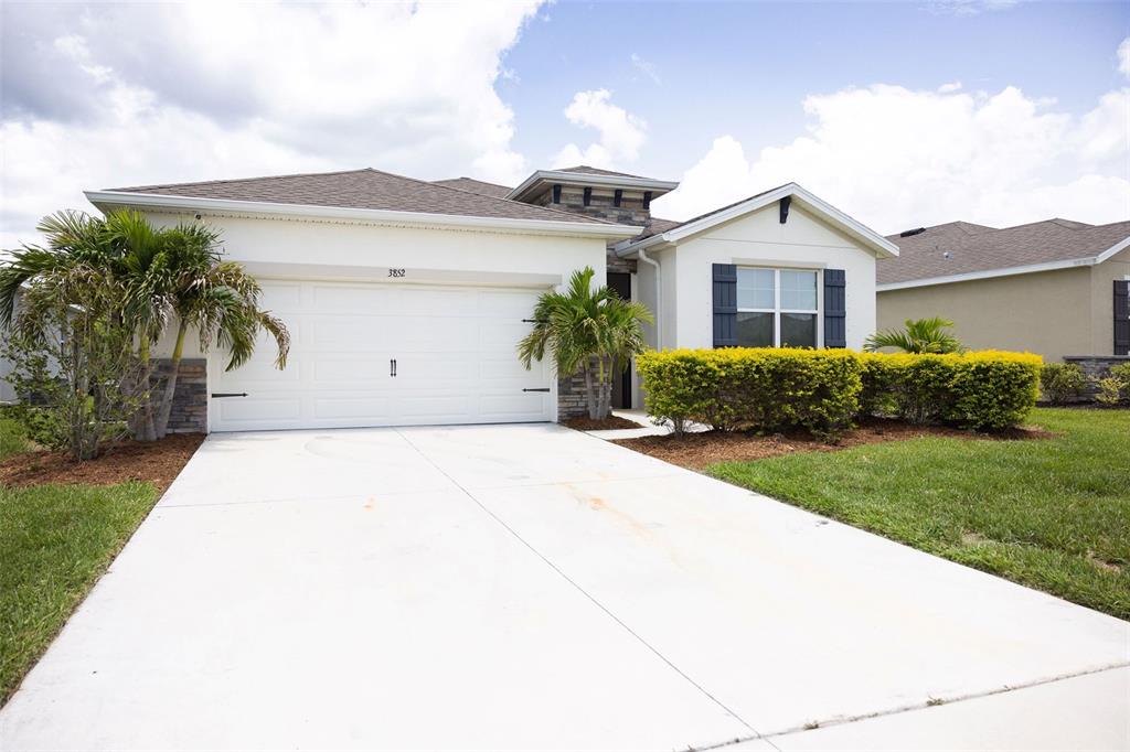 A single-story house with a white stucco exterior, a two-car garage, and palm trees — 3852 MOSSY LIMB COURT, PALMETTO, FL