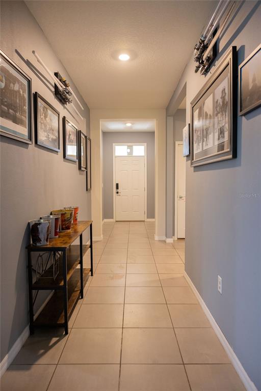 A hallway with tiled floors, gray walls, framed artwork, and a console table — 3852 MOSSY LIMB COURT, PALMETTO, FL