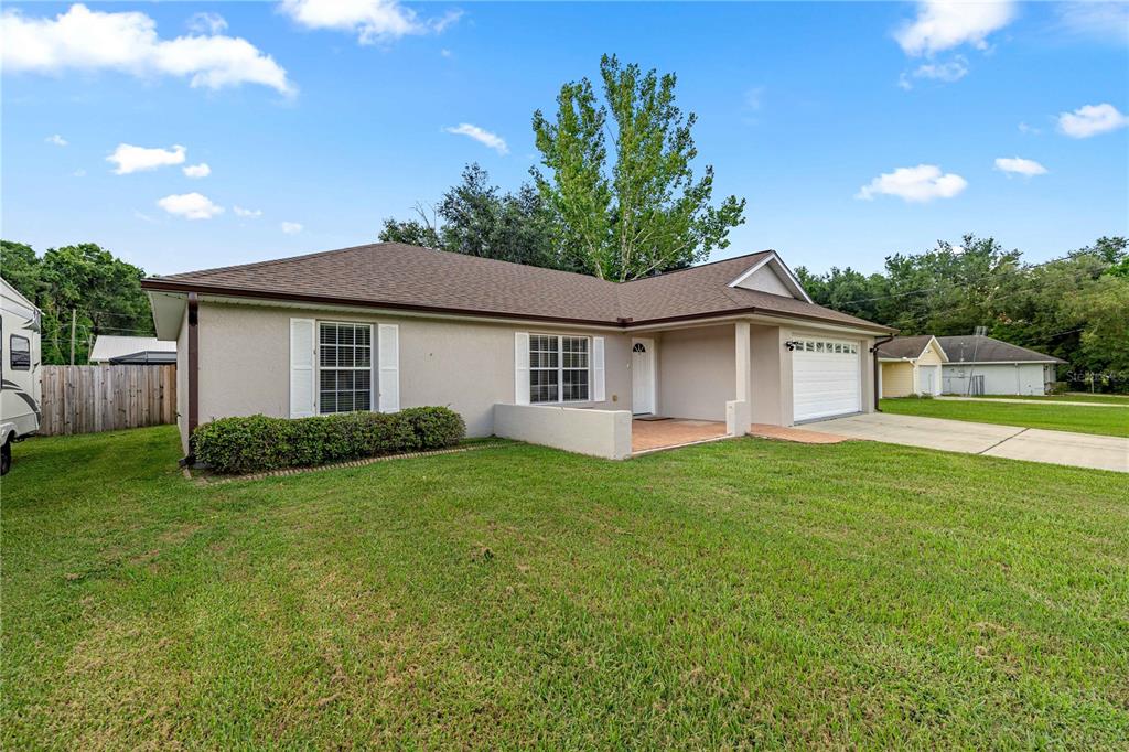 A single-story house with a beige stucco exterior, brown roof, and an attached two-car garage — 36 ALMOND DRIVE, OCALA, FL