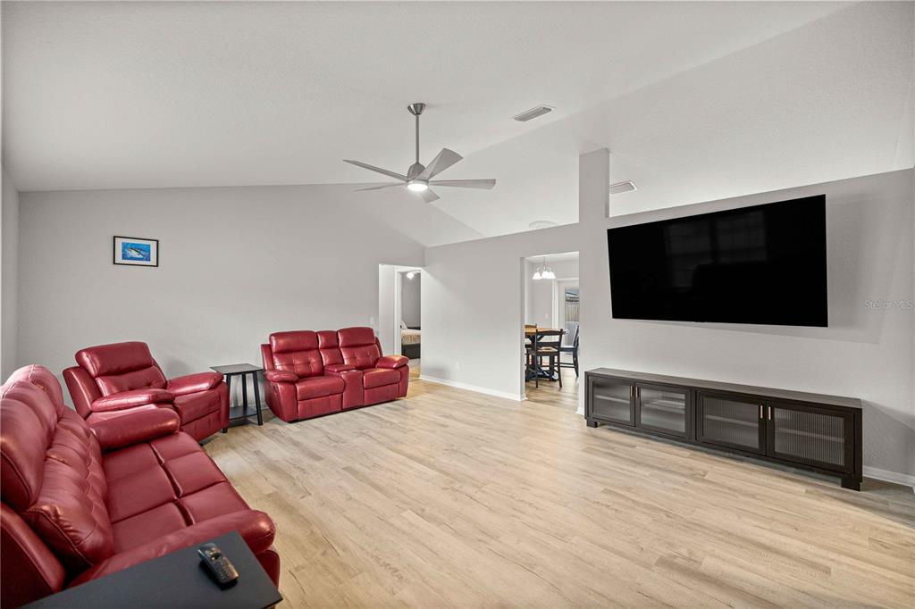 A living room features red leather furniture, a large wall-mounted television, and light wood flooring — 36 ALMOND DRIVE, OCALA, FL