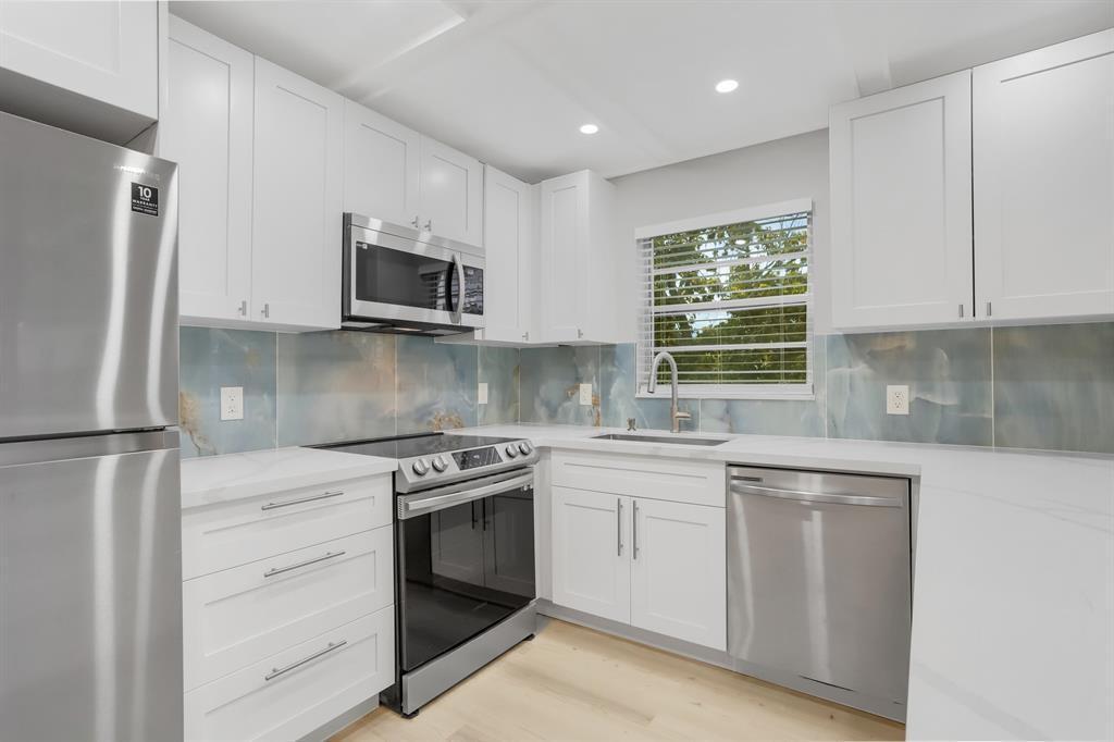 A kitchen features white cabinets, stainless steel appliances, and a blue marble-patterned backsplash — 40 Prescott B # 40, Deerfield Beach FL 33442, DEERFIELD BEACH, FL