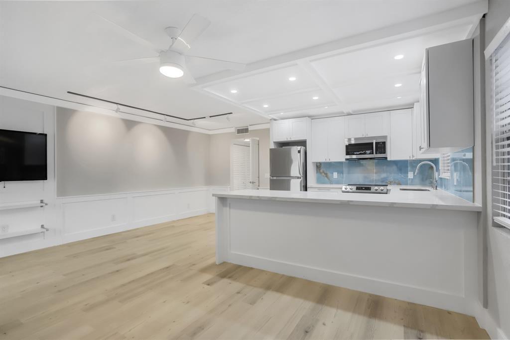 A modern kitchen with white cabinets and a blue backsplash opens to a living area — 40 Prescott B # 40, Deerfield Beach FL 33442, DEERFIELD BEACH, FL