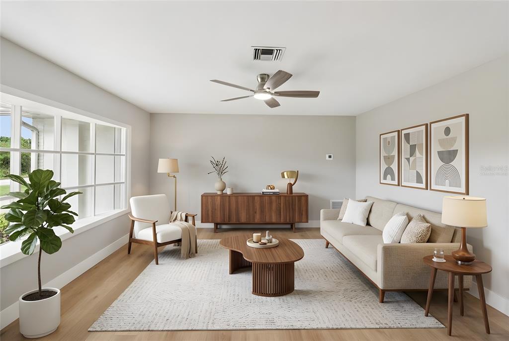 A living room features a beige sofa, wooden coffee table, sideboard, and a large window — 1412 DIGARMO TERRACE, DELTONA, FL