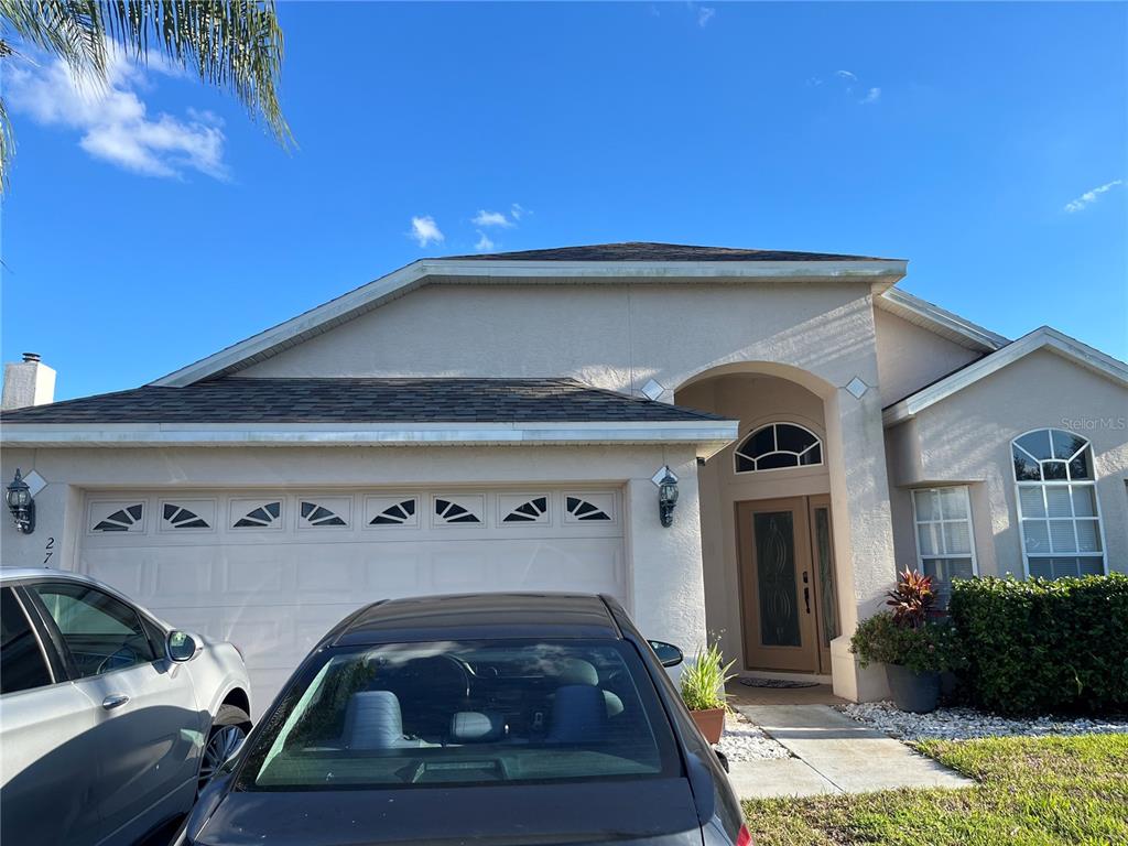 A beige single-story house features a two-car garage, a front entryway, and two parked cars — 2701 CRANE TRACE CIRCLE, ORLANDO, FL