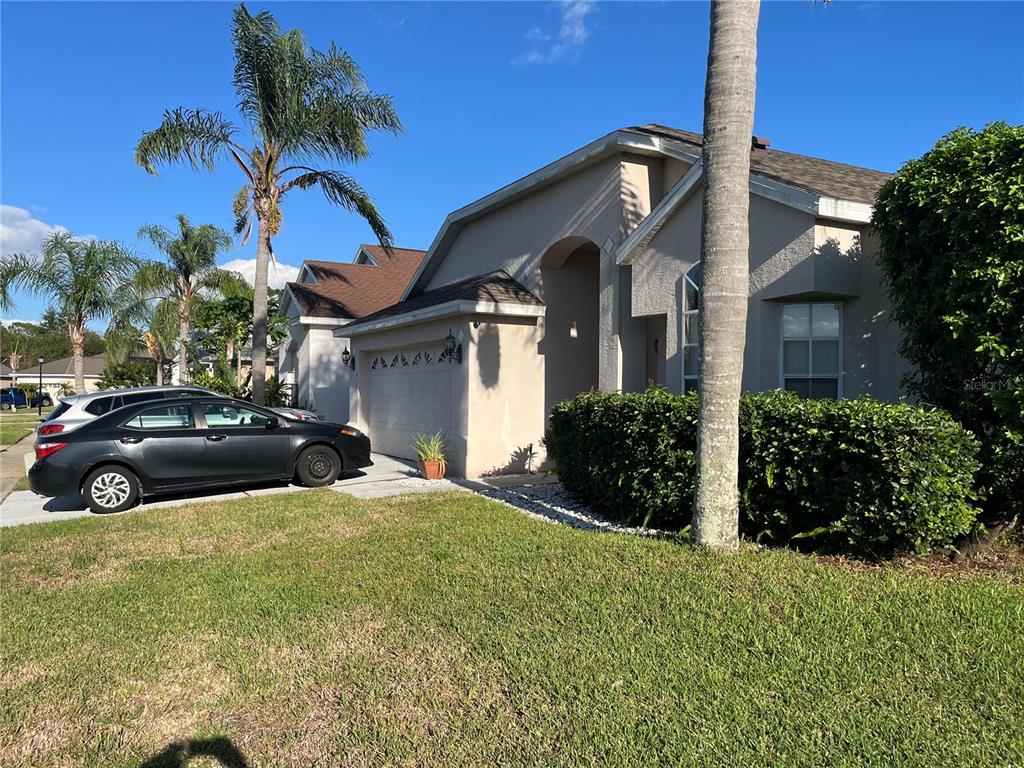 A single-story house with a beige stucco exterior, a two-car garage, and palm trees — 2701 CRANE TRACE CIRCLE, ORLANDO, FL