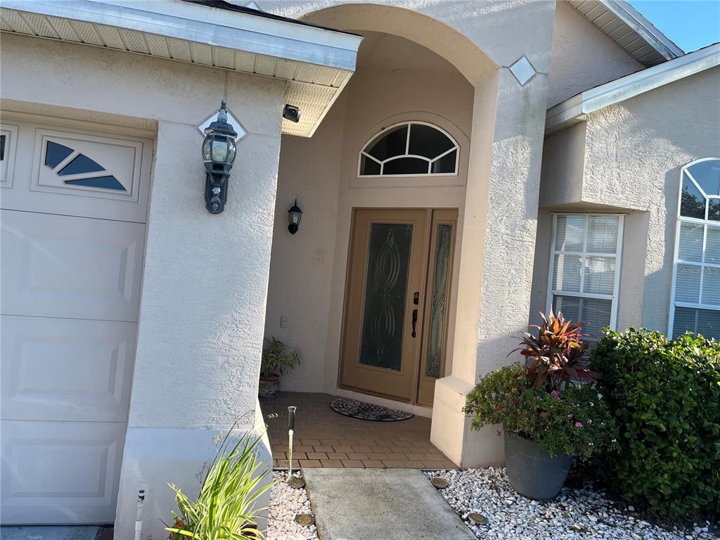 The exterior of a house features a tan front door, arched window, and garage — 2701 CRANE TRACE CIRCLE, ORLANDO, FL