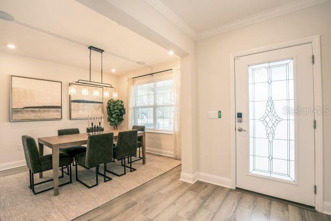 A dining area with a wooden table, dark chairs, and a glass-paneled front door — 16817 NW 176TH WAY, ALACHUA, FL
