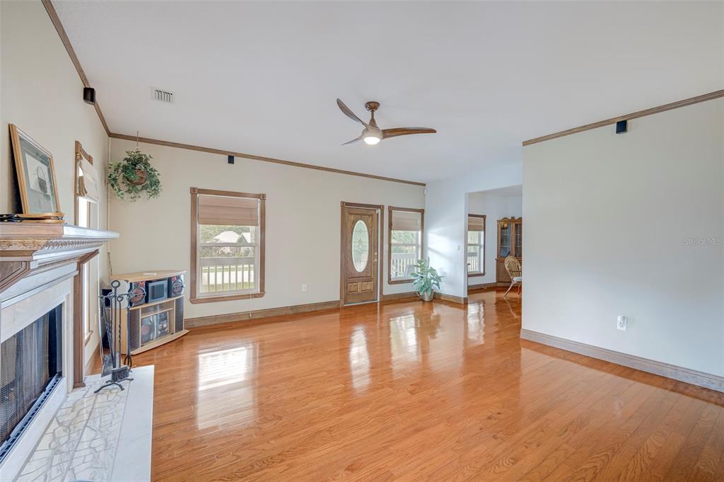 A living room features hardwood floors, a fireplace, a ceiling fan, and an entry door — 740 W VIRGINIA AVENUE, PUNTA GORDA, FL