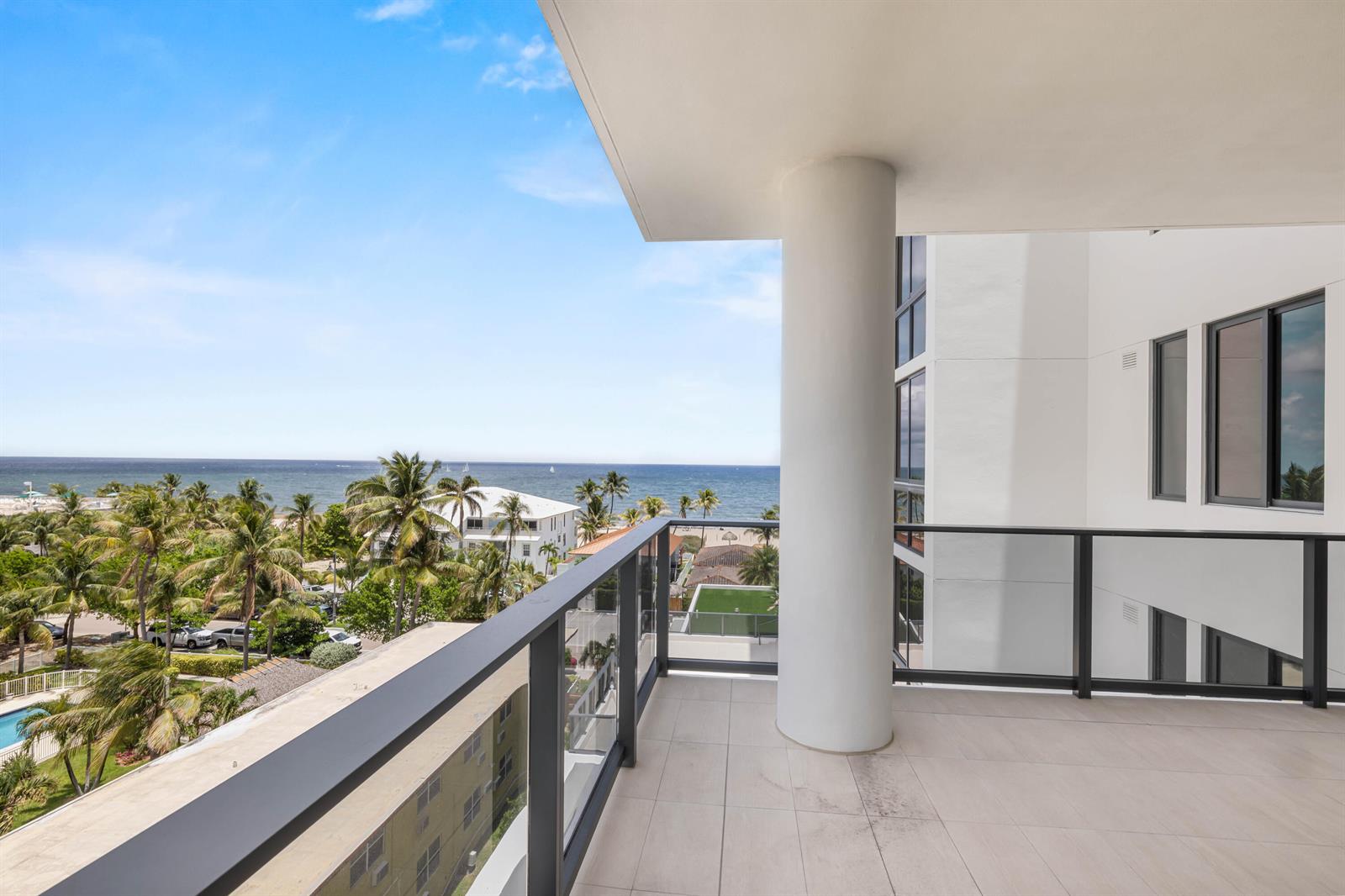 A balcony with a large white pillar, glass railings, and a view of the ocean — 305 Briny Avenue # 506, Pompano Beach FL 33062, POMPANO BEACH, FL