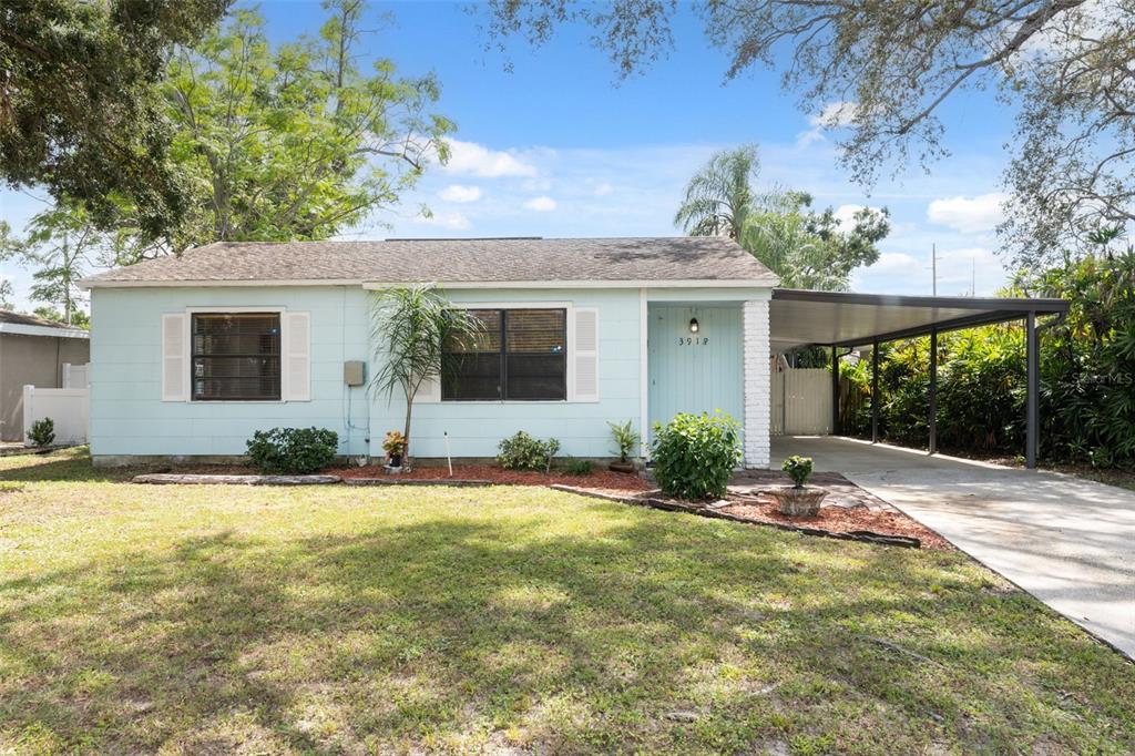 A light blue single-story house features a front lawn, a carport, and white shutters — 3918 W FIG STREET, TAMPA, FL