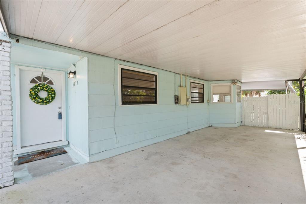 A covered concrete carport leads to a light blue house with a white front door — 3918 W FIG STREET, TAMPA, FL