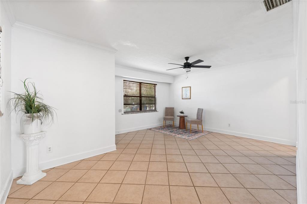A bright, tiled room features a small dining set, a ceiling fan, and a pedestal plant — 3918 W FIG STREET, TAMPA, FL