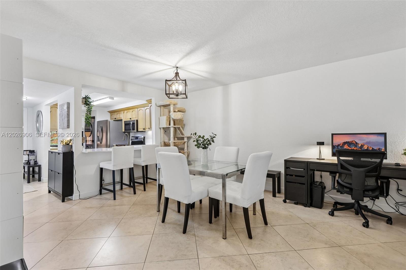 A dining area with a glass table, white chairs, and an adjacent home office space — 400 Commodore Dr # 206, Plantation FL 33325, PLANTATION, FL