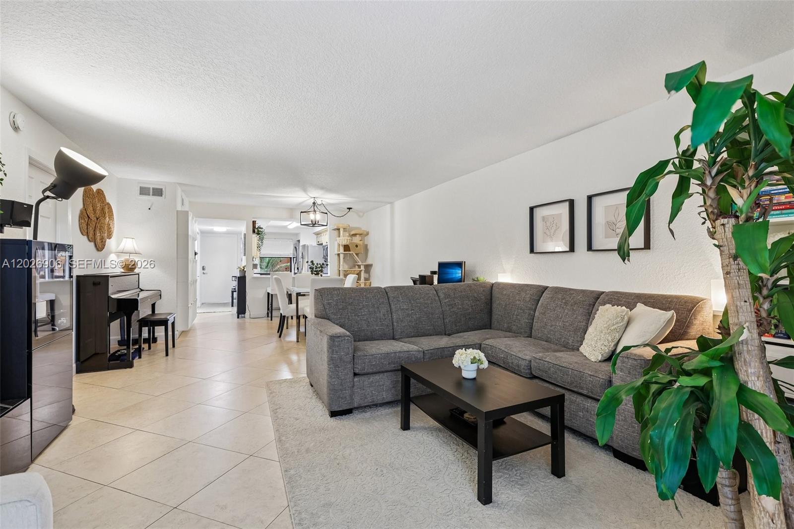 A living room features a grey sectional sofa, a coffee table, and a piano — 400 Commodore Dr # 206, Plantation FL 33325, PLANTATION, FL
