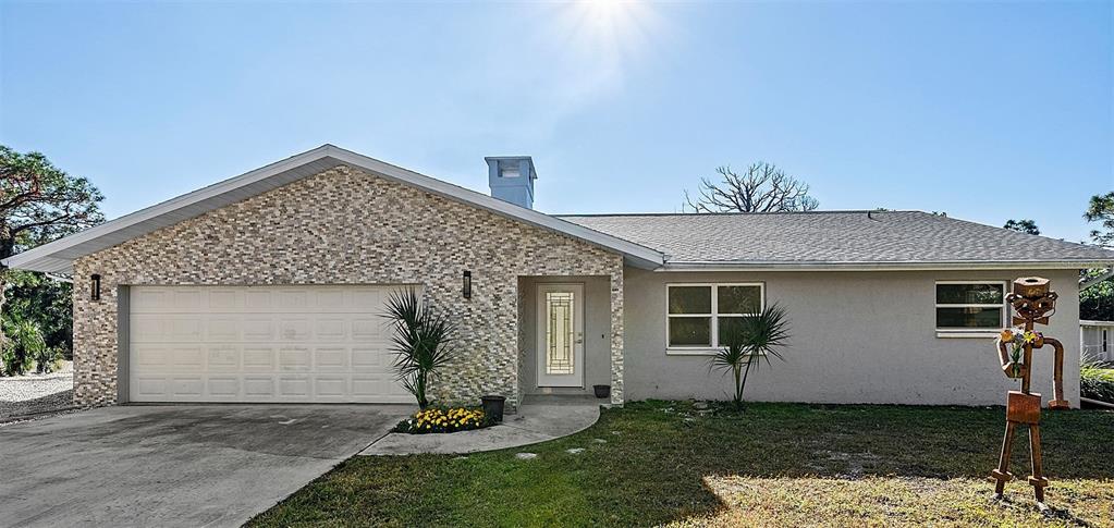 A single-story house features a stone-veneer facade, a two-car garage, and a metal sculpture — 700 FAITH AVENUE, OSPREY, FL
