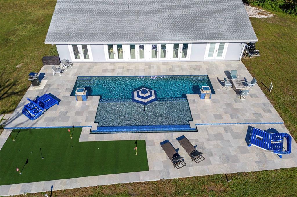 An aerial view shows a house with a swimming pool, putting green, and patio furniture — 700 FAITH AVENUE, OSPREY, FL