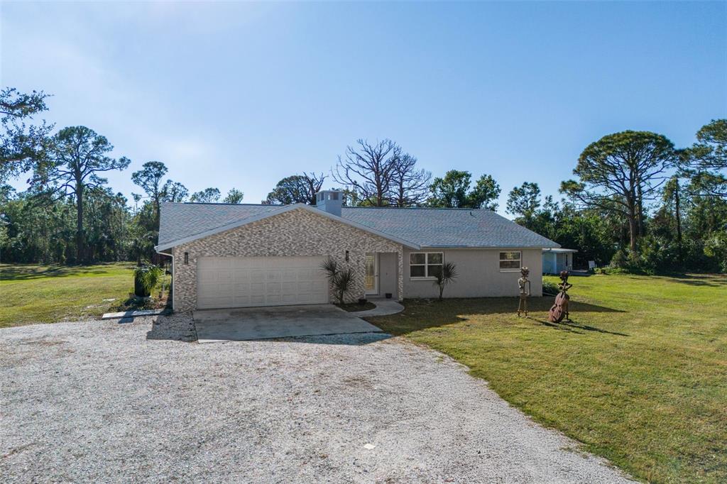 A single-story house with a stone-accented garage and a gravel driveway sits on a lawn — 700 FAITH AVENUE, OSPREY, FL