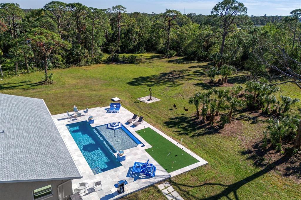 An aerial view of a backyard featuring a swimming pool, putting green, and patio furniture — 700 FAITH AVENUE, OSPREY, FL