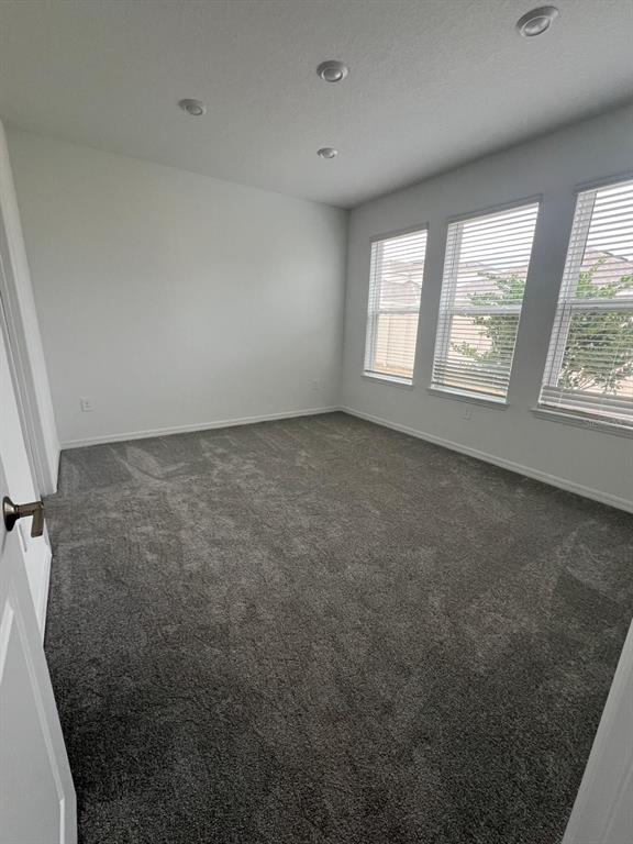 An empty bedroom with gray carpet, white walls, recessed lighting, and three windows with blinds — 5274 KILDARE PLACE, ST CLOUD, FL