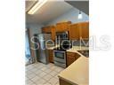 A kitchen features wood cabinets, stainless steel appliances, and light-colored tile flooring — 5433 LAKE MARGARET DRIVE UNIT E 195, ORLANDO, FL