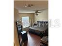 A bedroom features dark wood flooring, a ceiling fan, and a bed with dark bedding — 5433 LAKE MARGARET DRIVE UNIT E 195, ORLANDO, FL