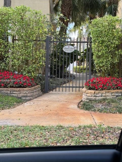 A paved courtyard leads to the double-door entrance of a yellow stucco house — 1659 Passion Vine Cir # 4, Weston FL 33326, WESTON, FL
