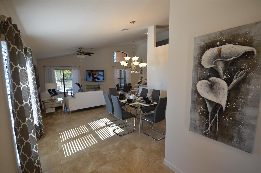 A dining area with a glass table and gray chairs sits beside a living room — 2647 TRANQUILITY WAY, KISSIMMEE, FL