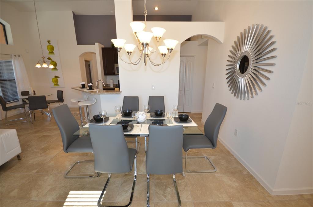 A dining area features a glass table, six gray chairs, and a sunburst wall mirror — 2647 TRANQUILITY WAY, KISSIMMEE, FL