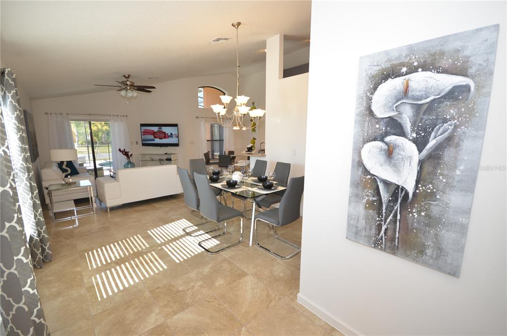 A dining area and living room feature tile floors, a chandelier, and a large painting — 2647 TRANQUILITY WAY, KISSIMMEE, FL