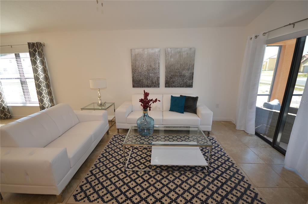 A living room features two white sofas, a glass coffee table, and a patterned rug — 2647 TRANQUILITY WAY, KISSIMMEE, FL