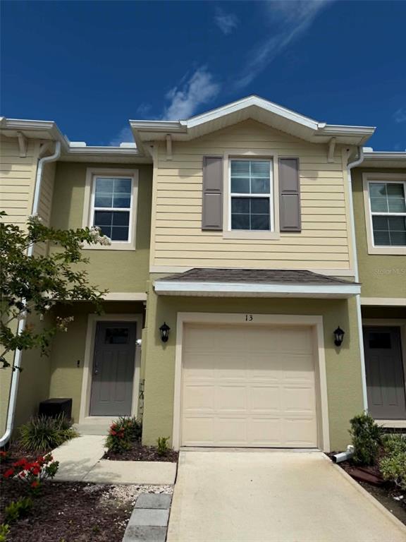 A two-story townhouse exterior features a beige garage, a gray front door, and tan siding — 13 BELLA OAKS DR DRIVE, PORT ORANGE, FL