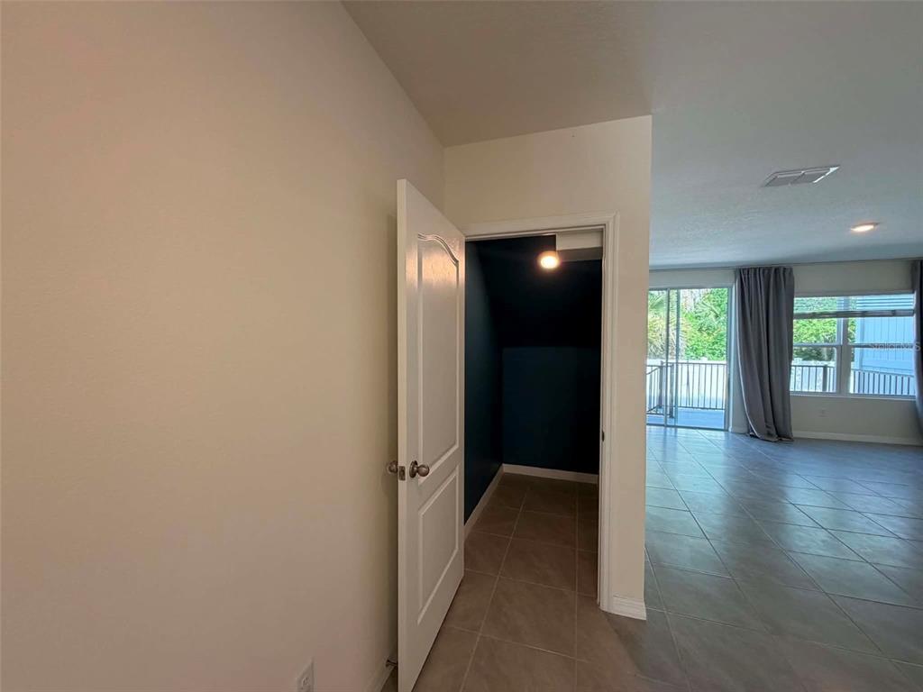 A view from a hallway into a small dark-walled closet and an adjacent living area — 13 BELLA OAKS DR DRIVE, PORT ORANGE, FL